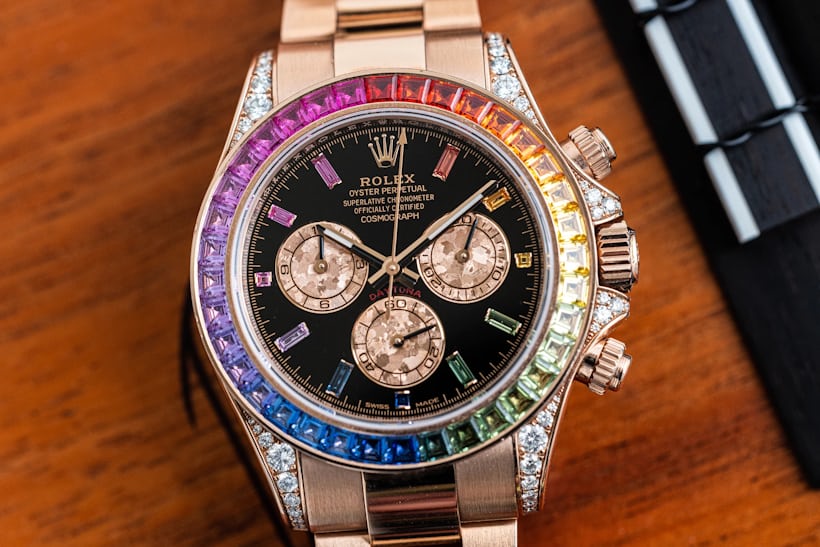 Close up of a rose gold rainbow rolex daytona on a wooden surface