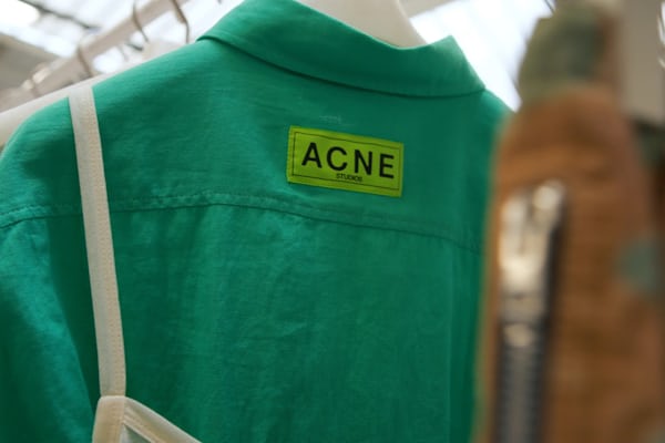 Closeup of a green shirt with a light green tag that reads "ACNE Studios"