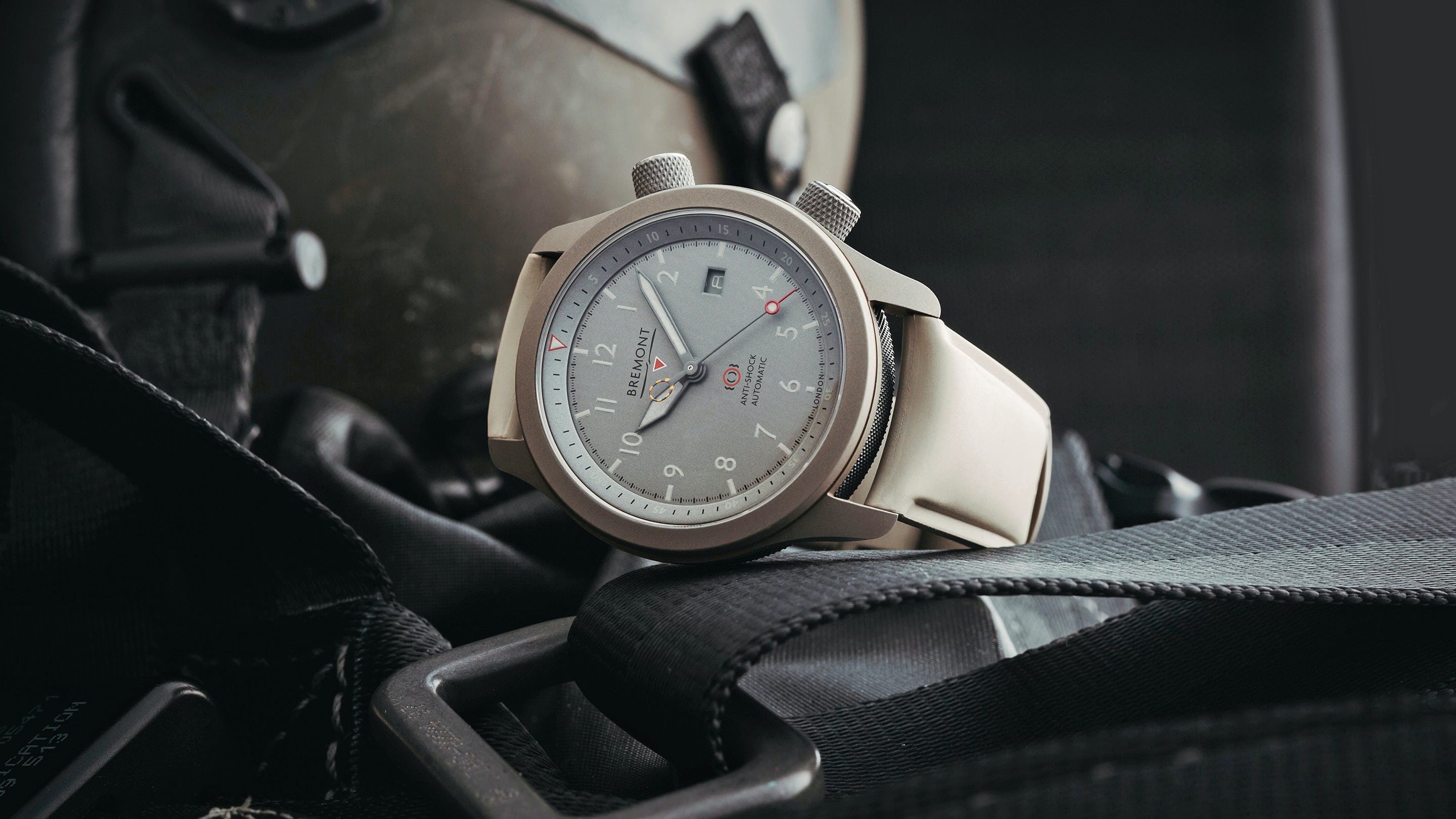 A Bremont MBII Savanna In Titanium leaning on its side surrounded by airplane equipment.