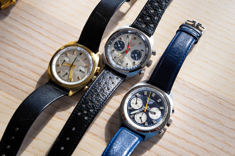 Three carrera chronographs with c-shaped cases laid out on a wooden surface
