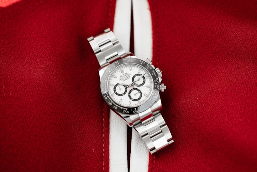A Rolex Daytona watch with a white dial rests on top of a red and white fabric