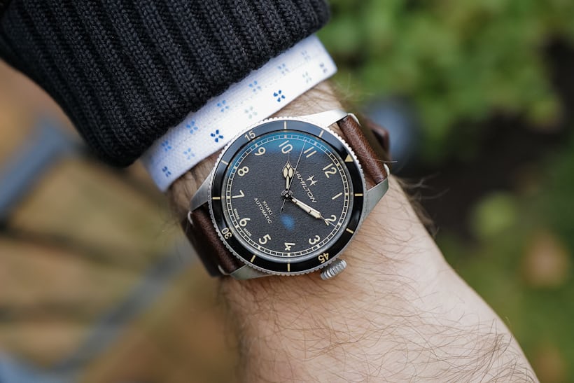 The Hamilton Khaki Pilot Pioneer in 38mm size on wrist with a brown leather jacket.