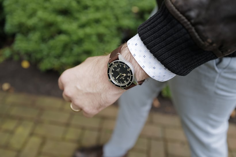 The Hamilton Khaki Pilot Pioneer in 38mm size on wrist with a brown leather jacket while walking.