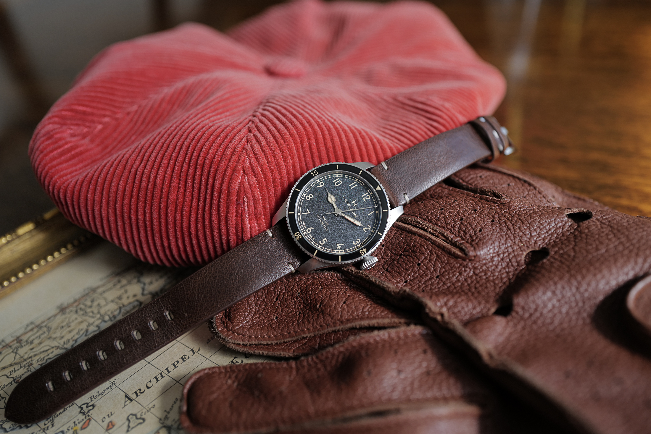 The Hamilton Khaki Pilot Pioneer in 38mm size on a red hat with driving gloves.