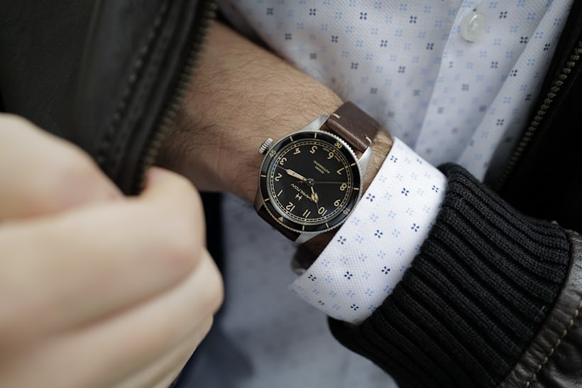 The Hamilton Khaki Pilot Pioneer in 38mm size on wrist, hand reaching into pocket of brown leather jacket.