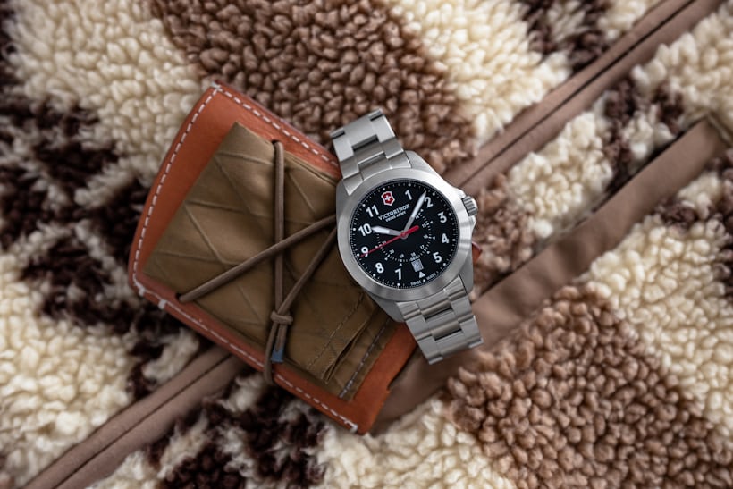 The Victorinox Heritage sitting on a jacket with a brown wallet. 