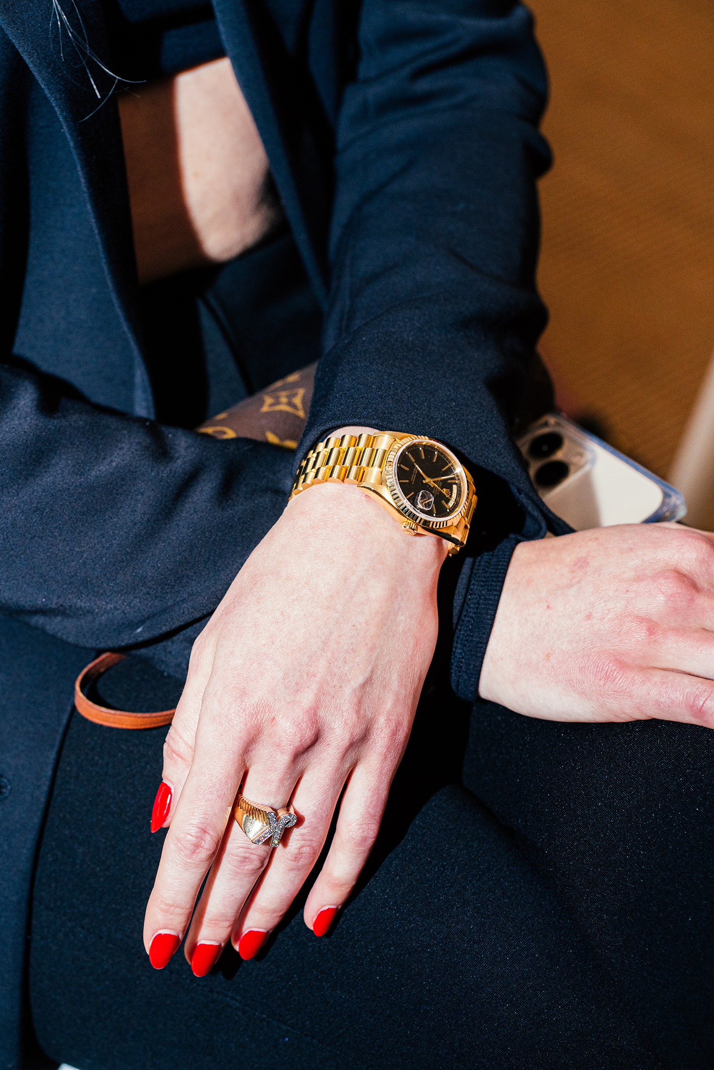 A person with red nails wearing a gold watch