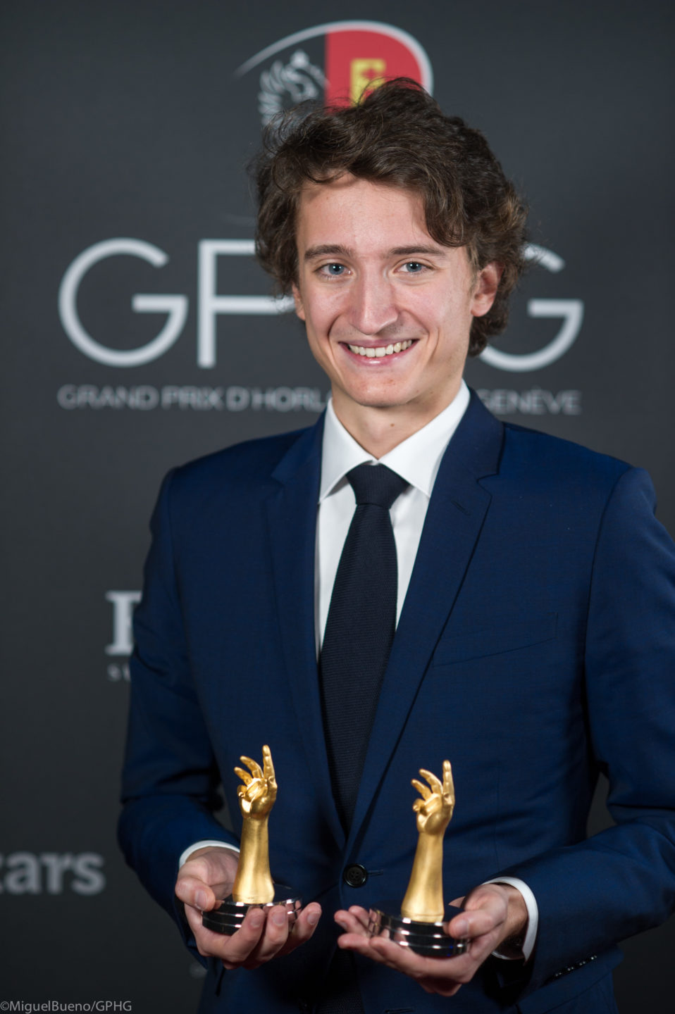 A Louis Vuitton Watch executive holding two GPHG trophies. 