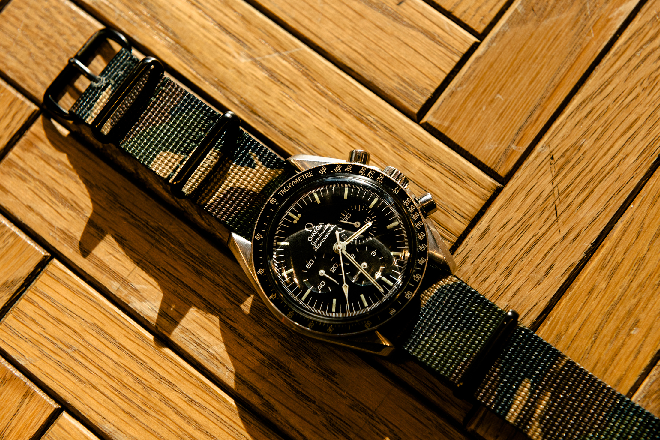 An black Omega Speedmaster on a wood background