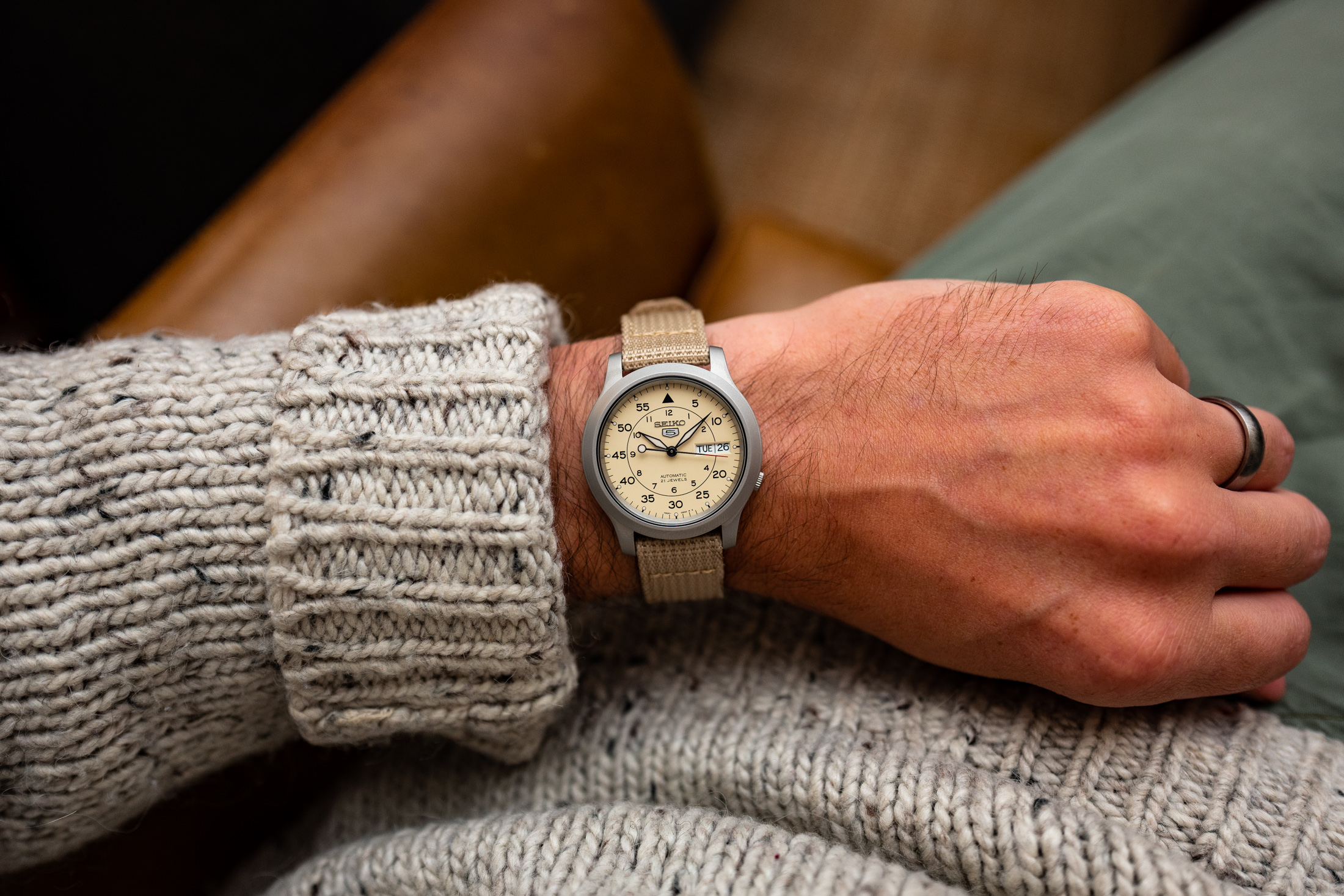 A person wearing a sweater and a Seiko 5 watch