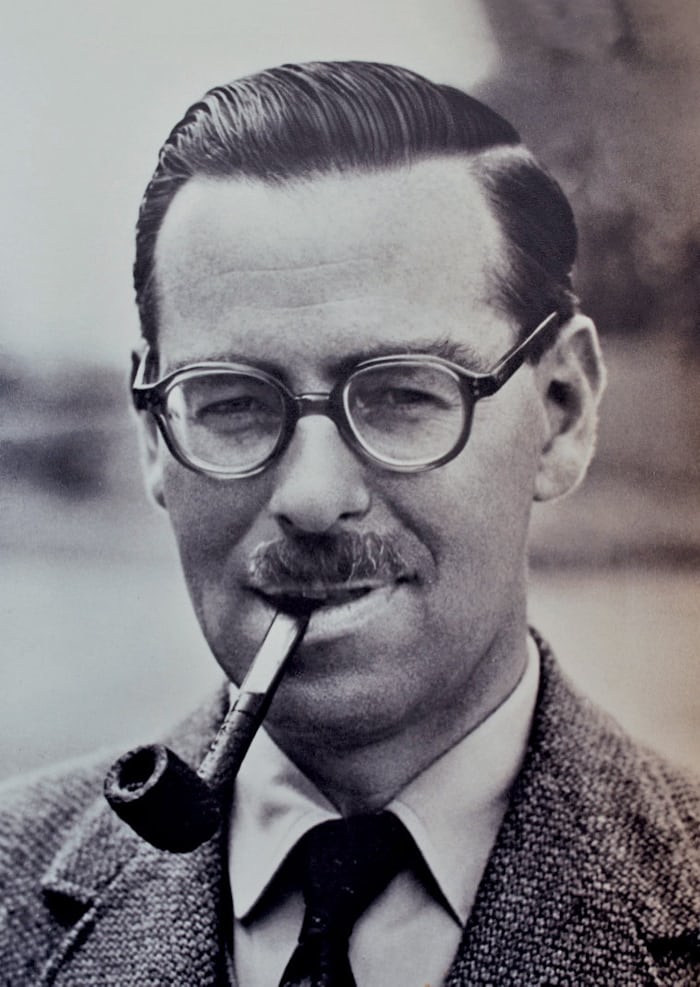 A man wearing glasses and smoking a pipe 