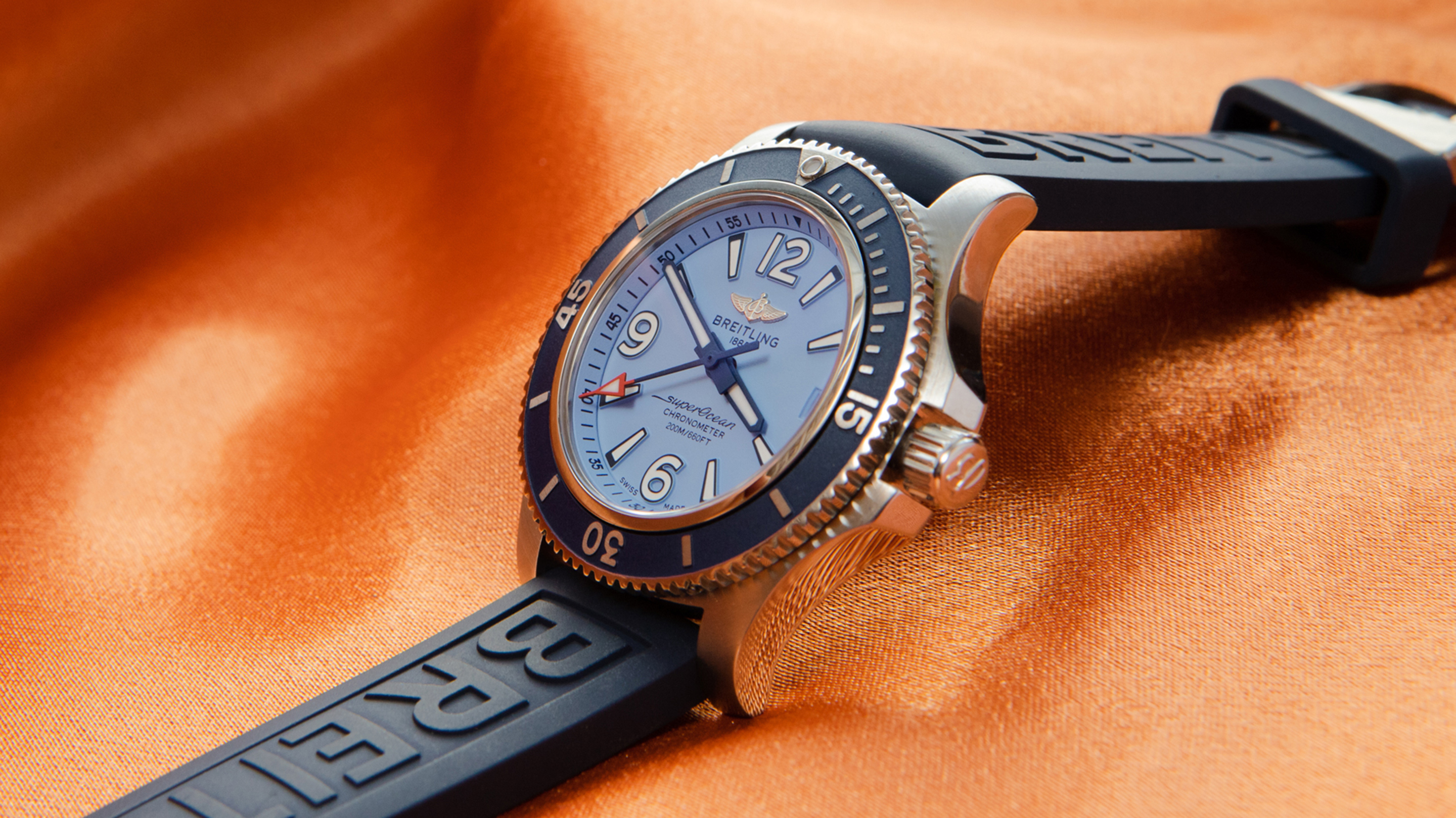 A blue Breitling watch on an orange background