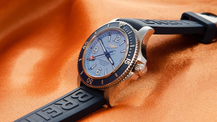 A blue Breitling watch on an orange background