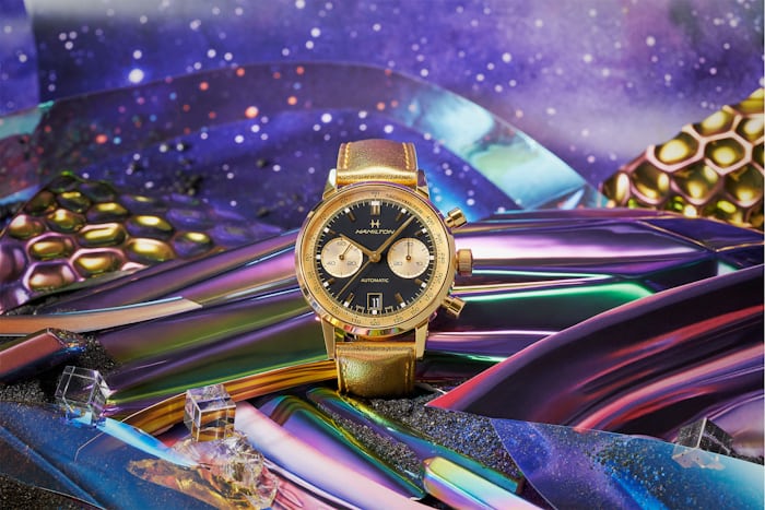 A gold Hamilton watch on a psychedelic background