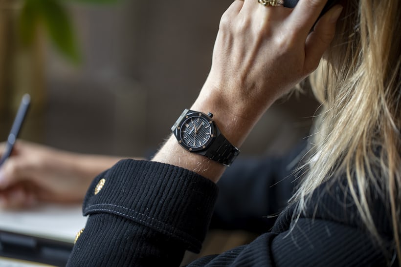 A black Royal Oak on the wrist of someone who is writing