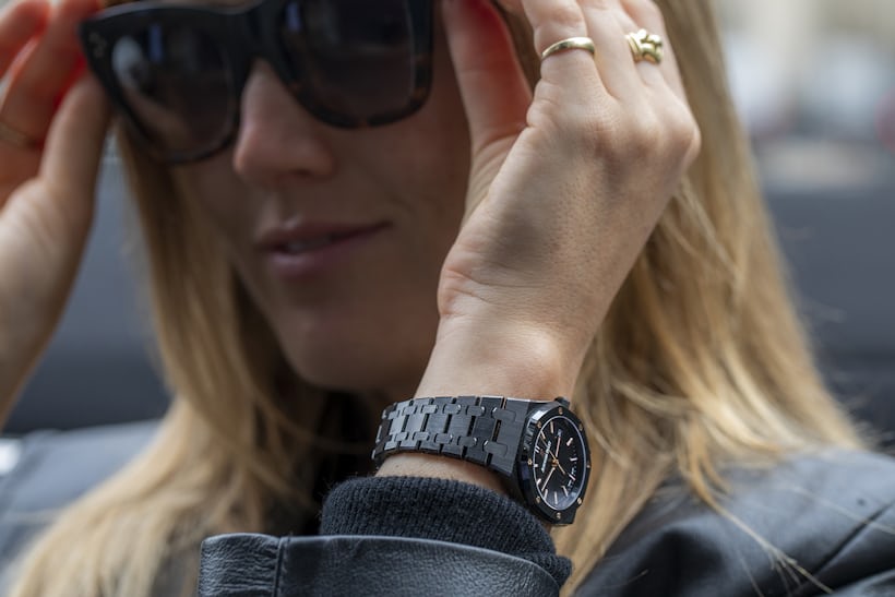 A person putting on sunglasses with a Royal Oak watch on their wrist