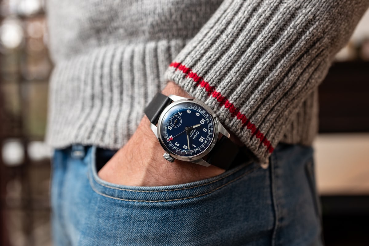 An Oris BC 403 on wrist with a grey sweater and jeans. 
