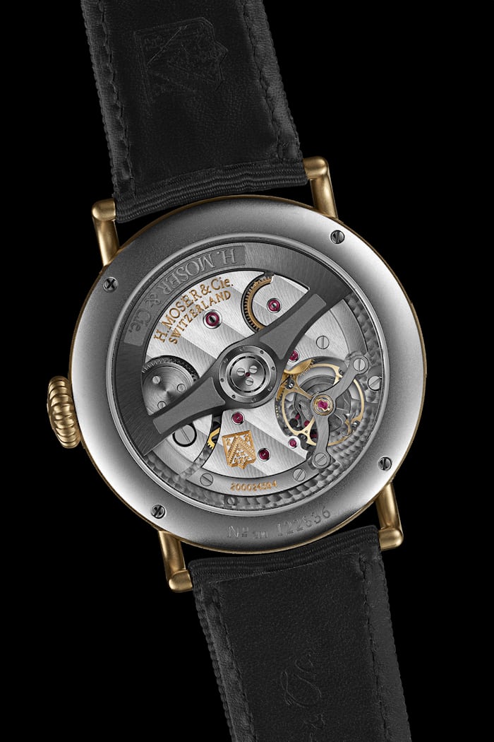 The caseback of an H. Moser watch on a black background