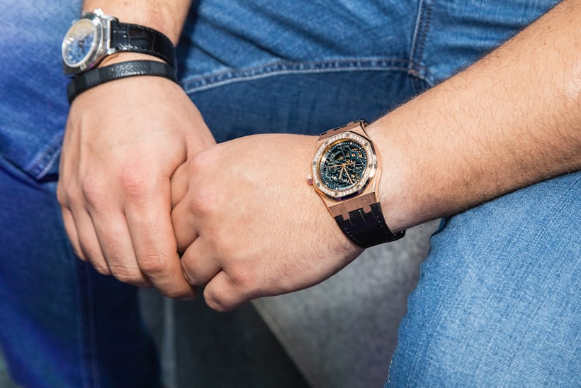 A person wearing two watches and blue jeans