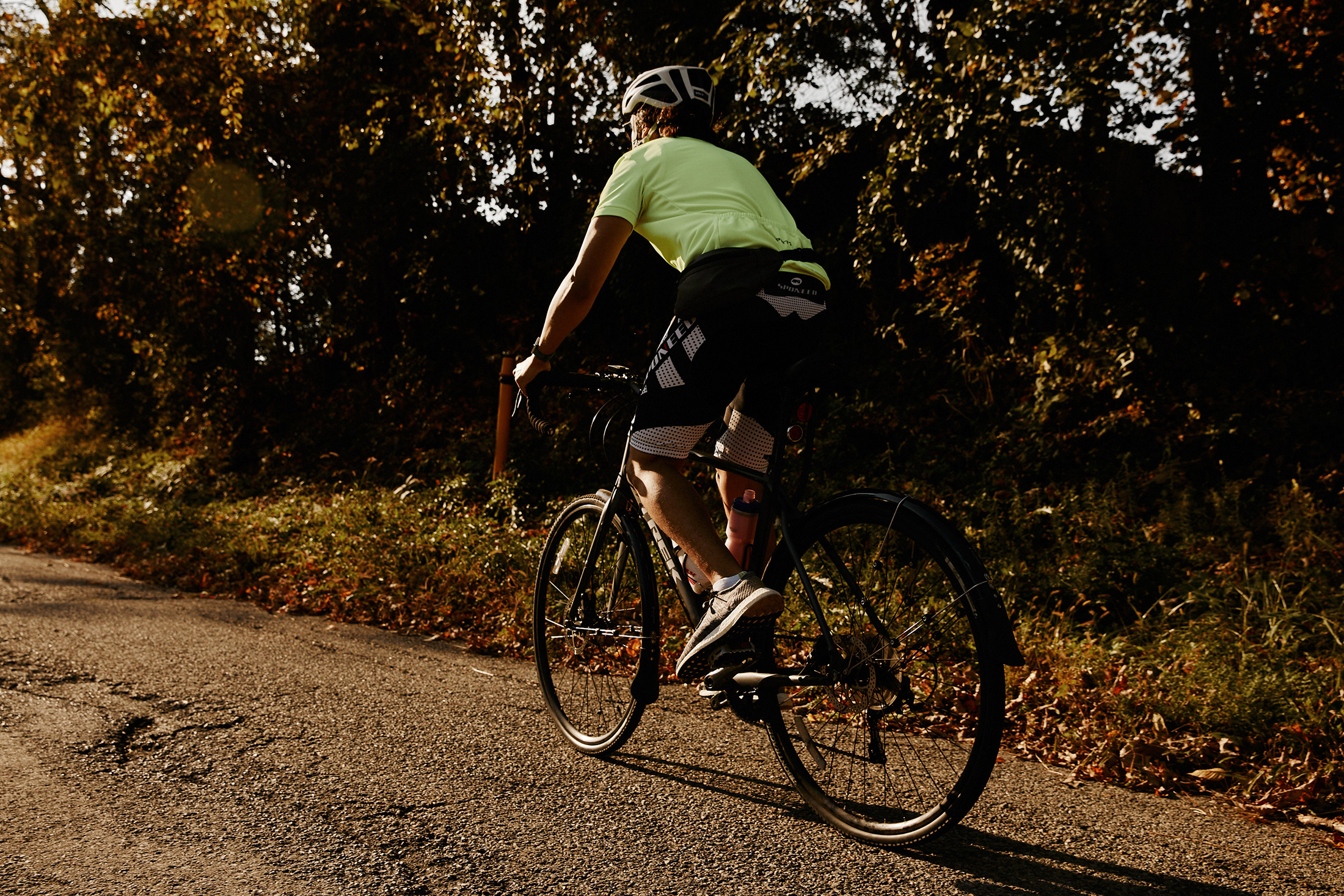 A person on a bike with a green shirt and bike helmet