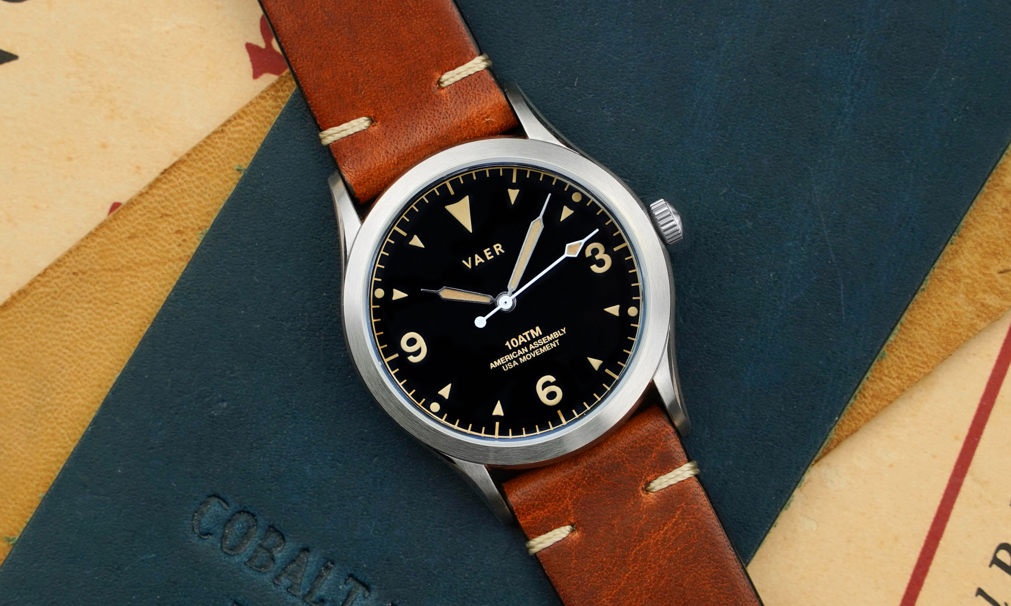 A black dial field watch with tan accents on a leather strap.