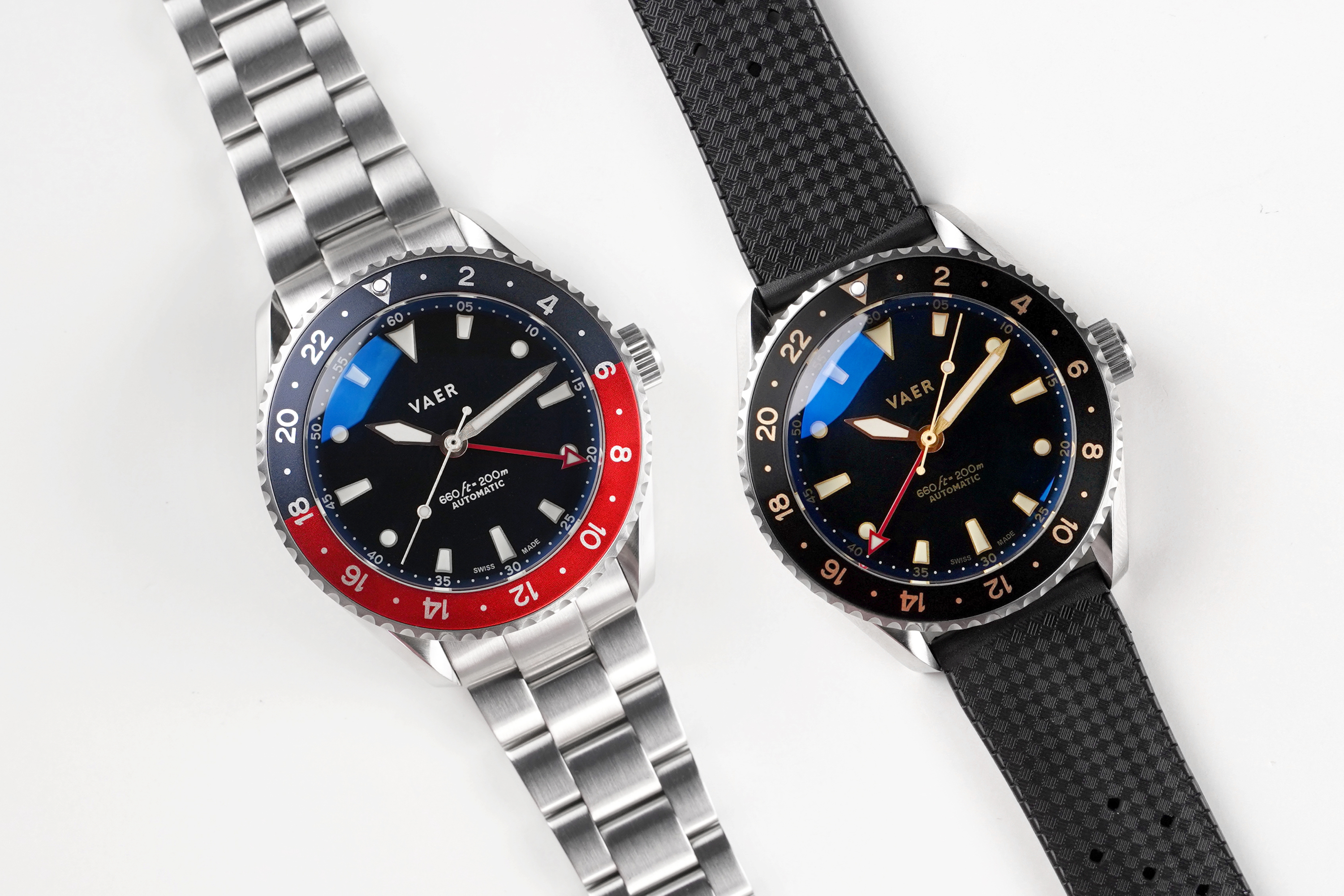 Two GMT watches laying side by side. One has a red and blue bezel, the other has a black bezel.