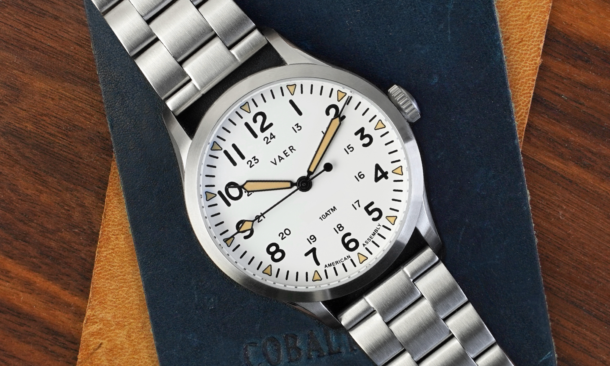 A white dial field watch on a bracelet.