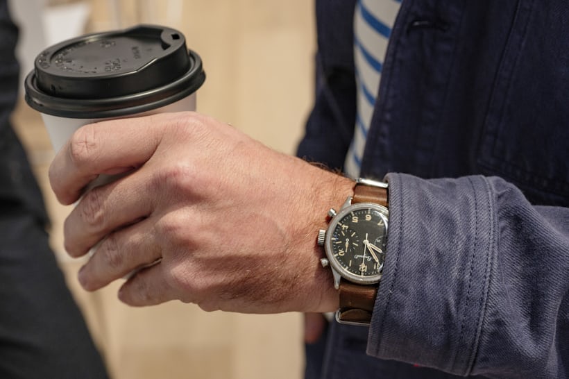 A man wears a vintage Breguet Type XX and holds a cup of coffee.