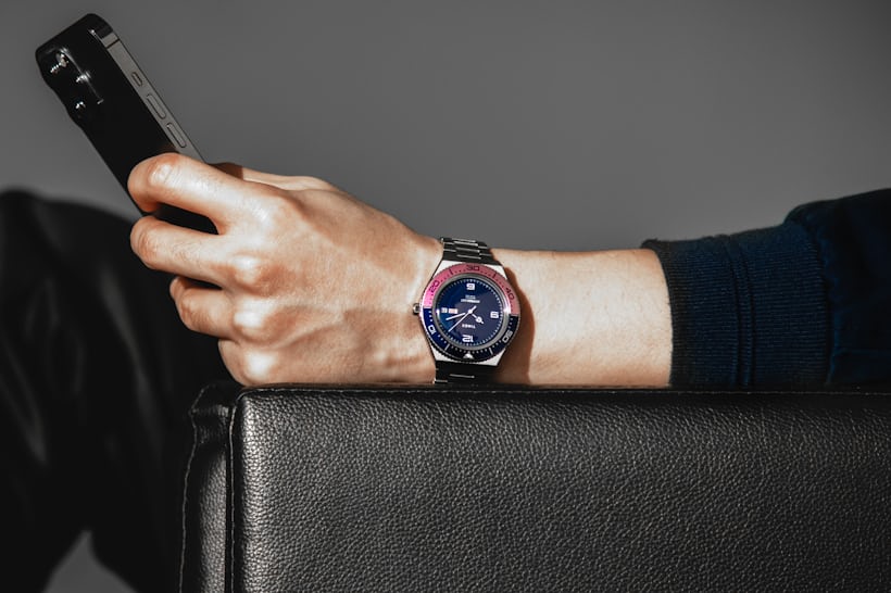 A man wears a Timex M79 'Fuchsia' Limited Edition while holding his cell phone.