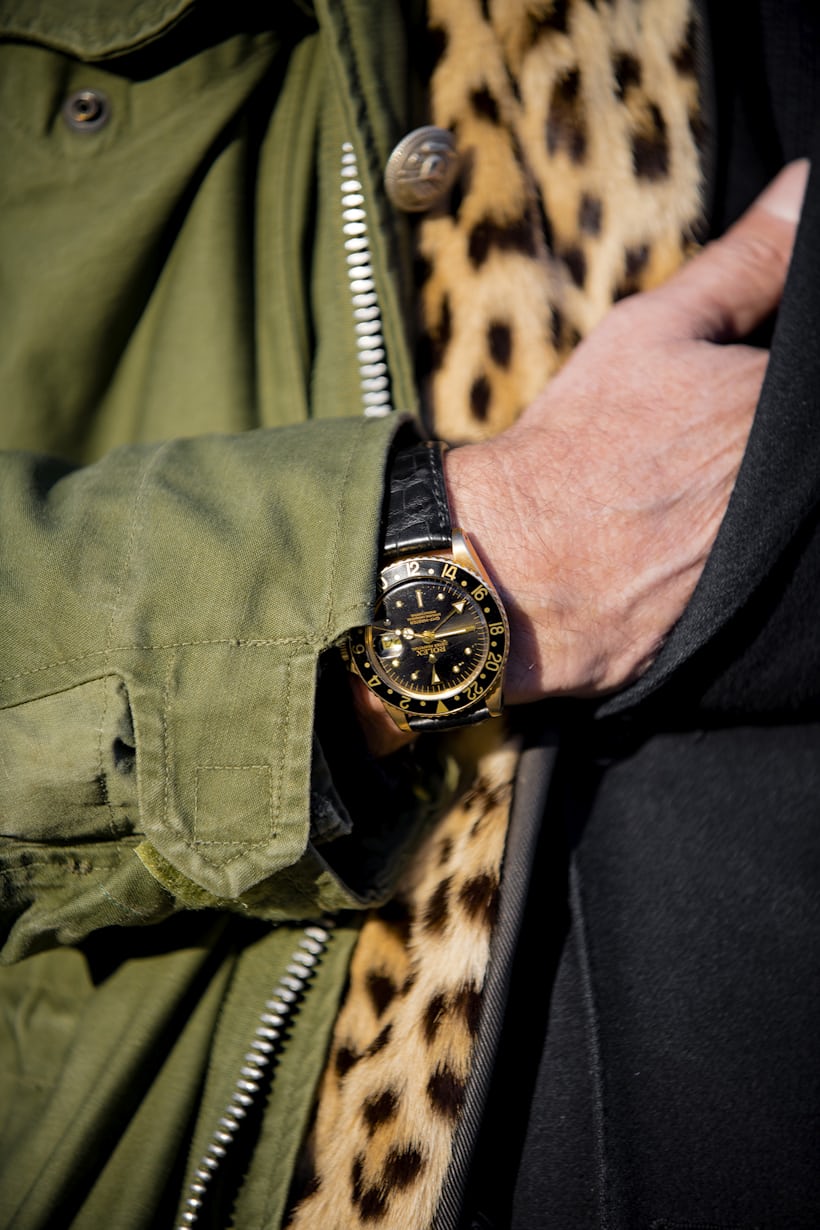 A watch on a wrist of a person wearing a leopard print scarf 