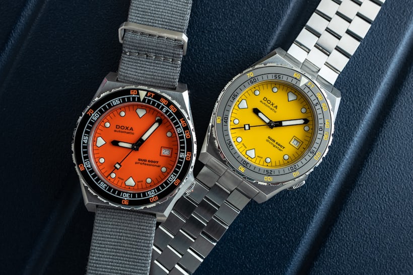 Both a yellow and an orange Doxa 600T on a blue background. 
