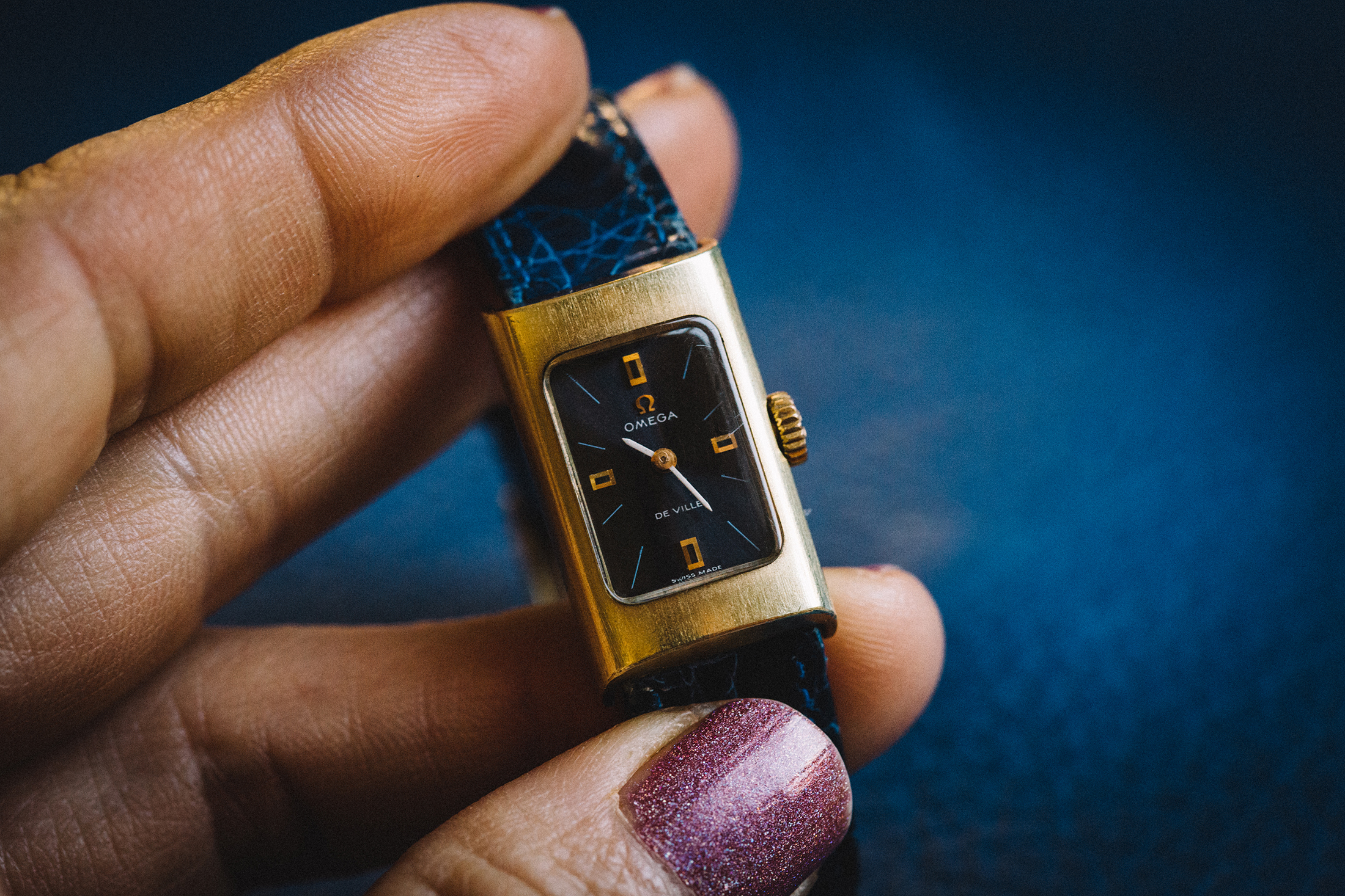 A hand holds an Omega De Ville