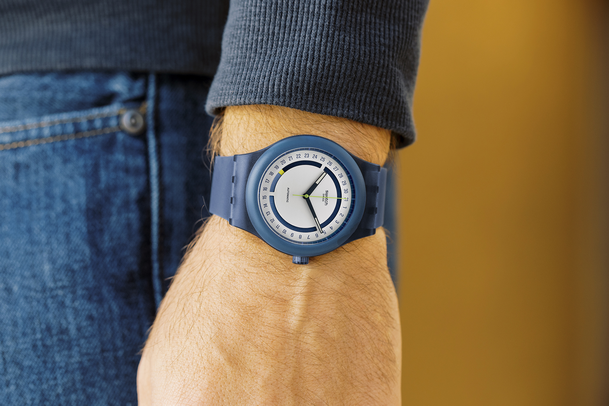 The SWATCH SISTEM51 HODINKEE STOPLIGHT NEON REMIX on a man's wrist.