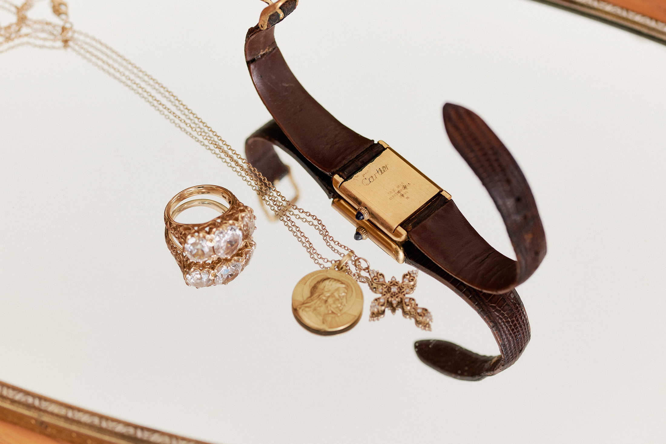 The caseback of a cartier watch, a pendant and an engagement ring