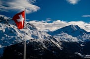 The Swiss flag in front of mountains