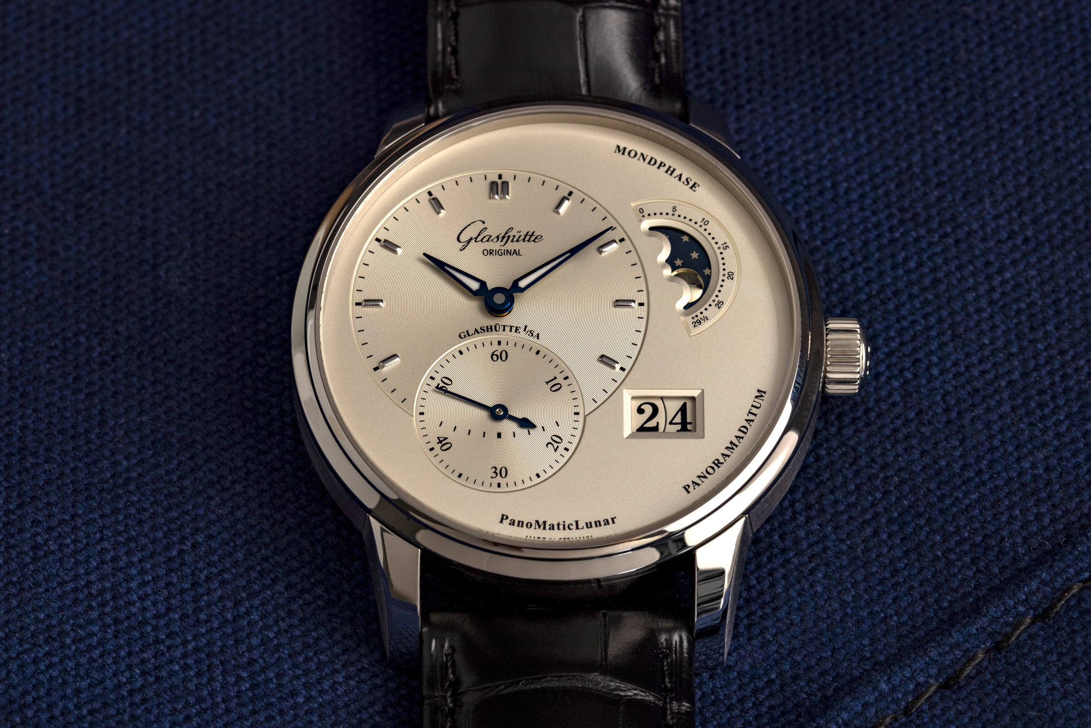 The Glashütte Original PanoMaticLunar ref. 1-90-02-42-32-05 rests on a blue fabric surface. 