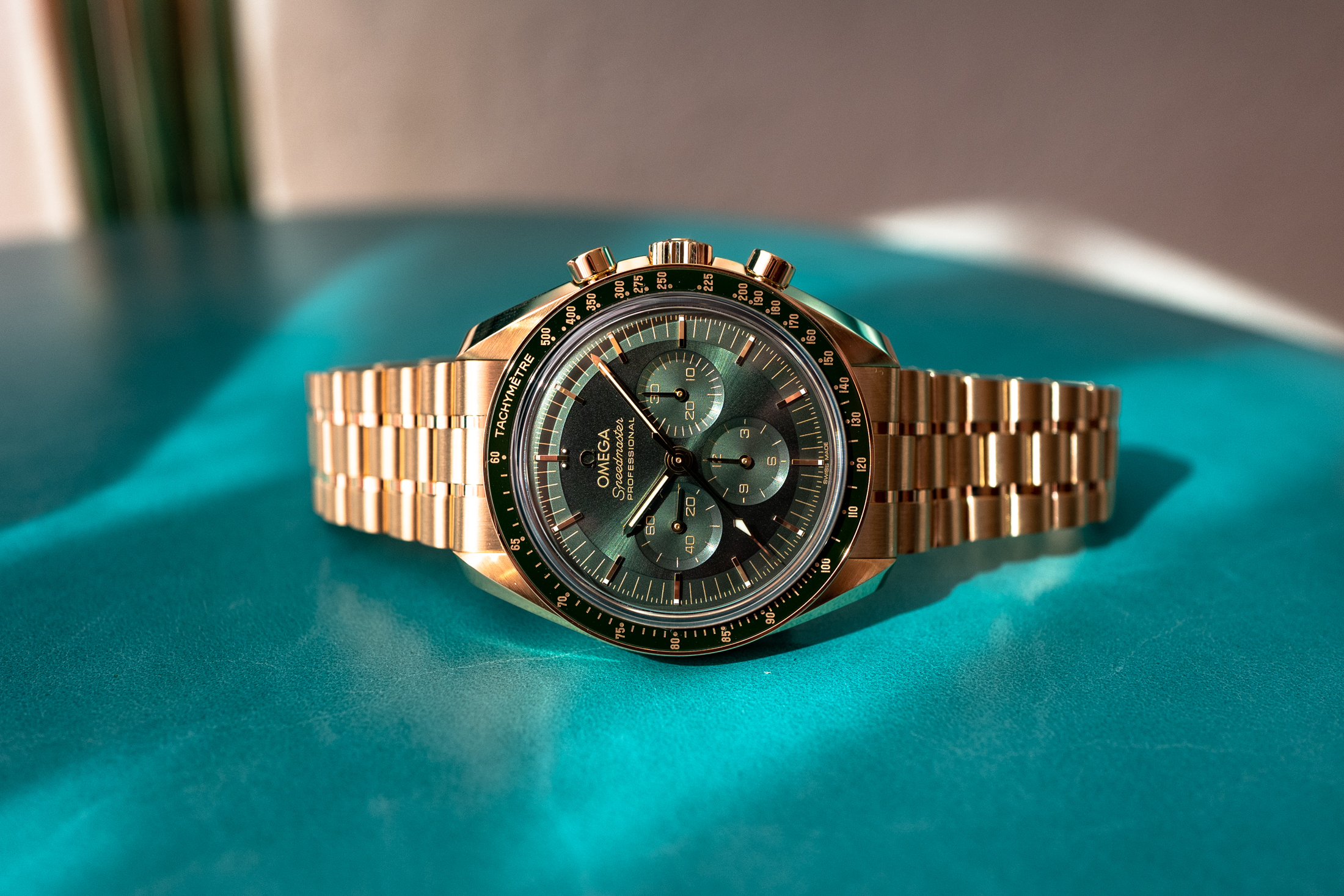 the green dial version of the new Moonshine Speedmaster on a blue/green background. 