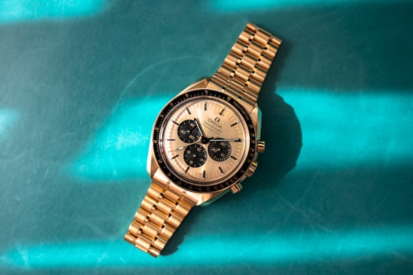 The gold dial moonshine speedmaster on a blue background
