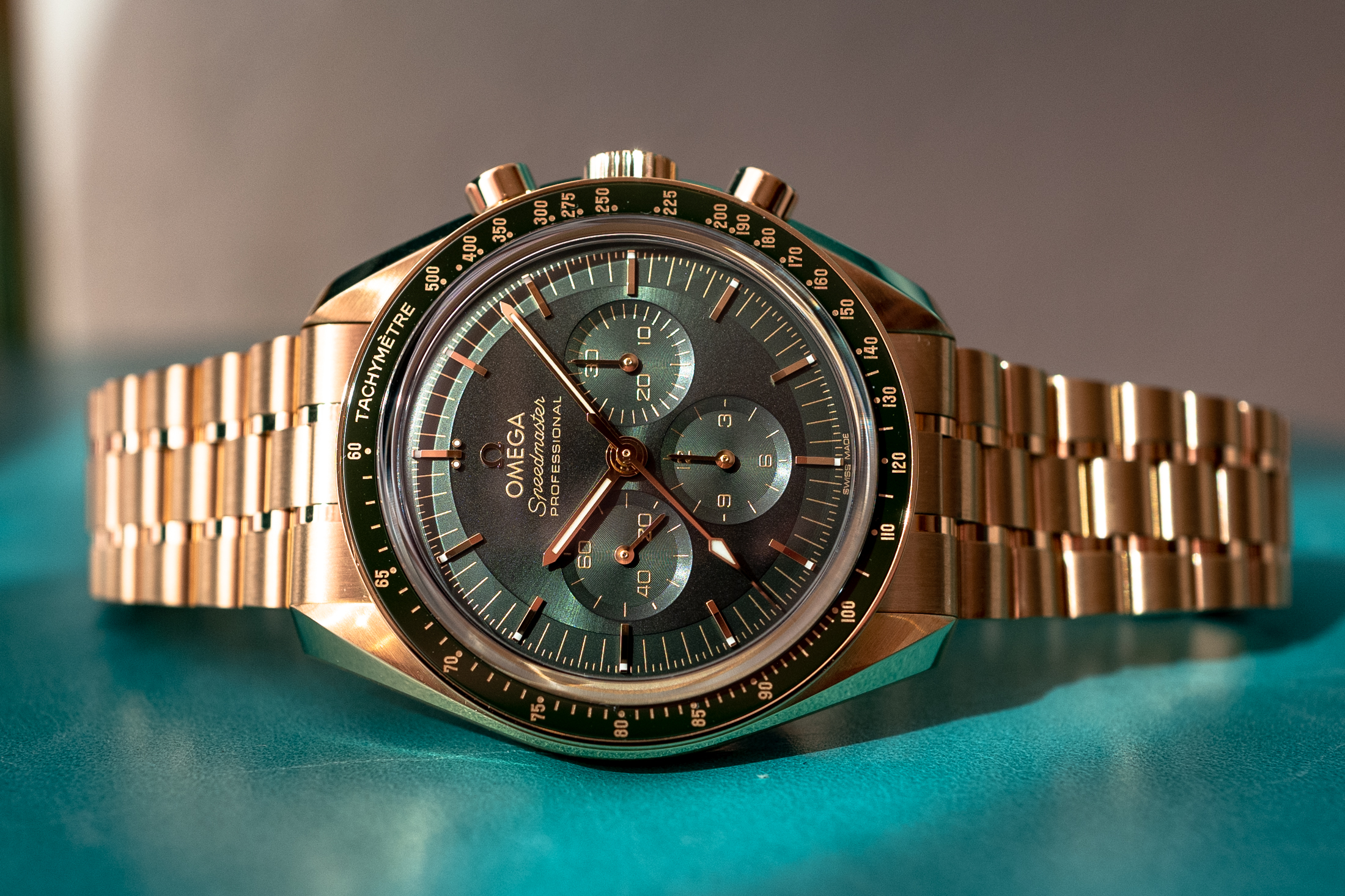 The green dial moonshine speedmaster on a blue background