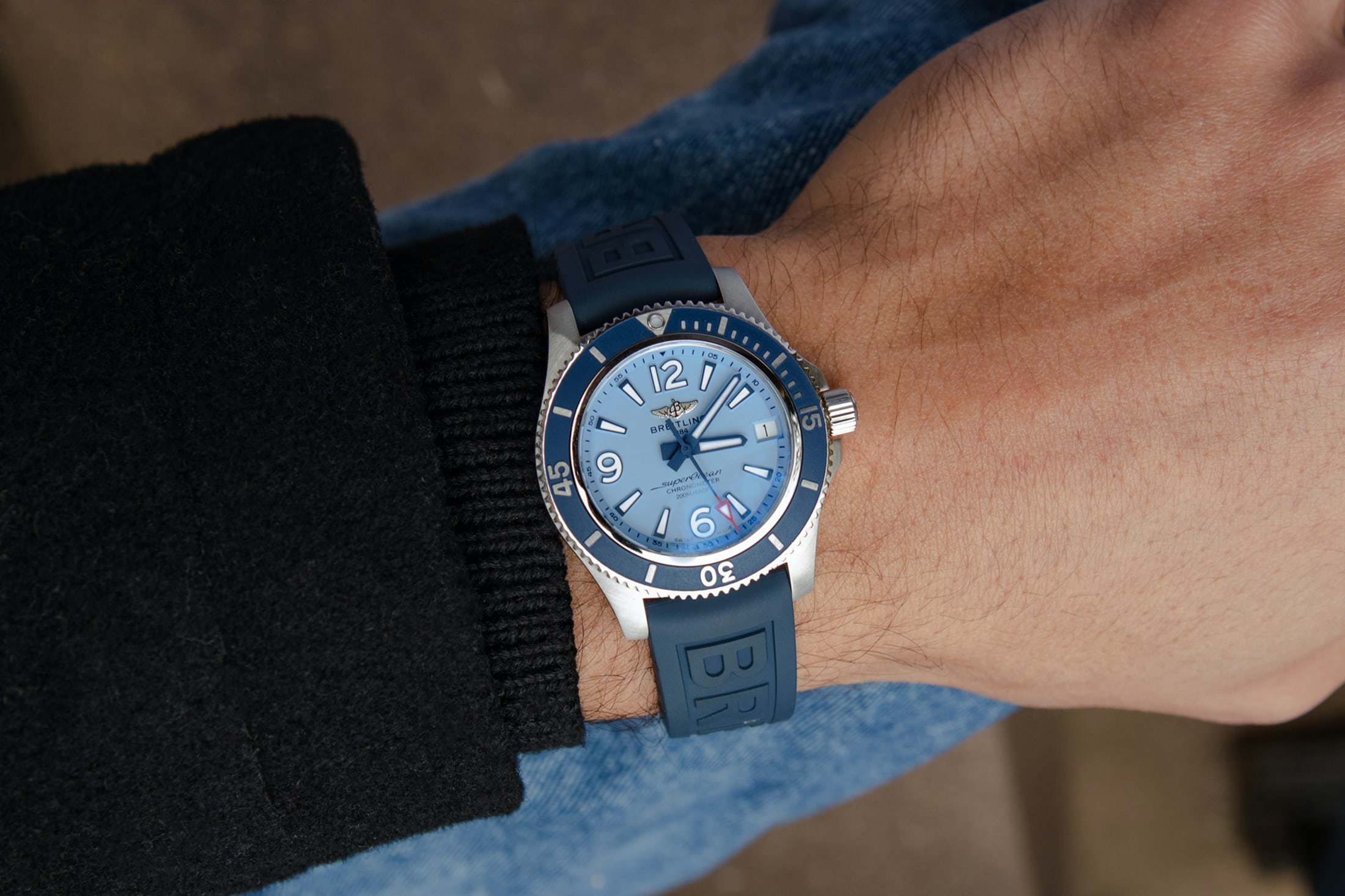 A man wears a Breitling Superocean with a light blue dial. 