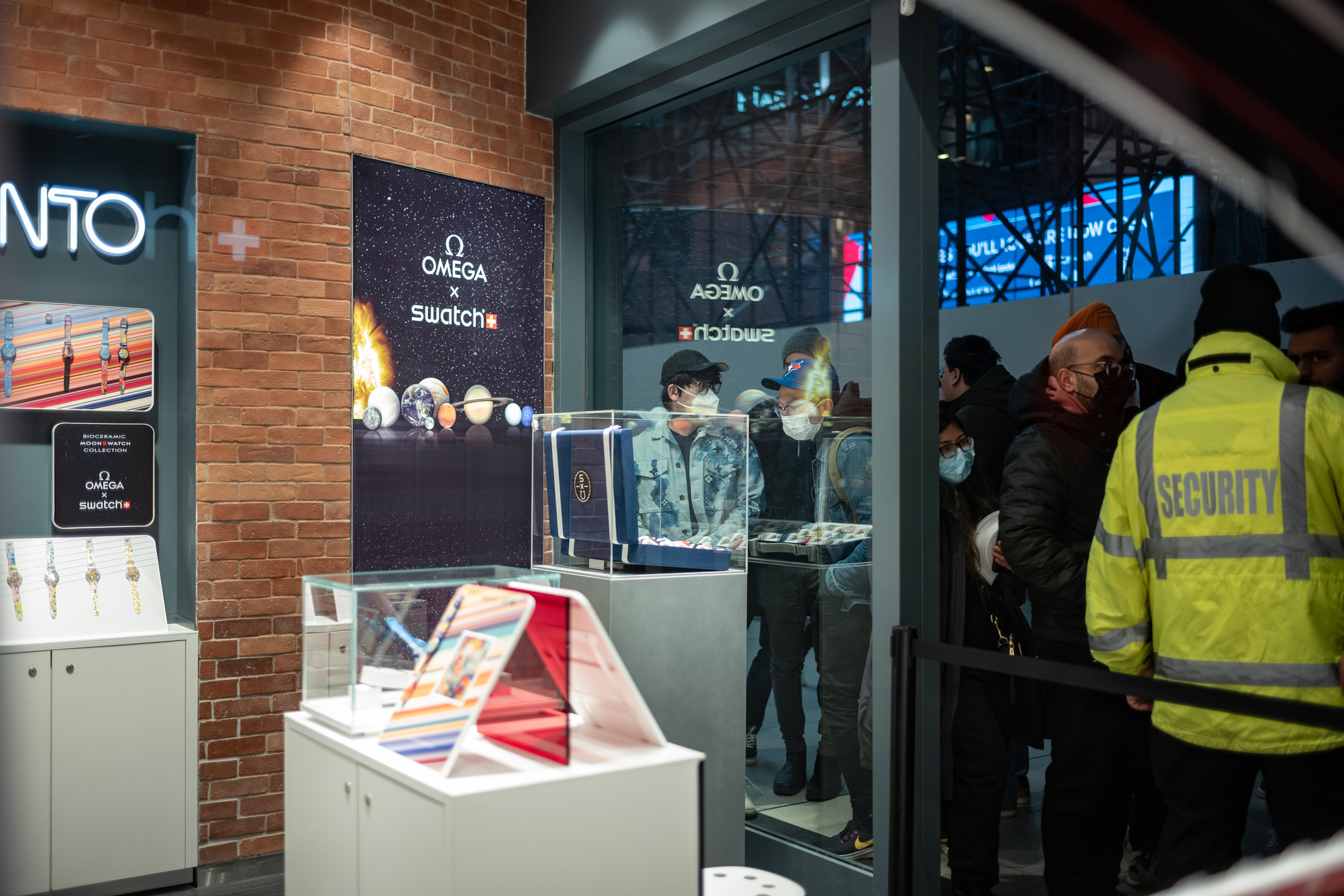 inside at the Swatch boutique in Toronto, a crowd gathers to take photos of the collection while others wait for their number to be called, hoping they will get their preferred Moonswatch version.