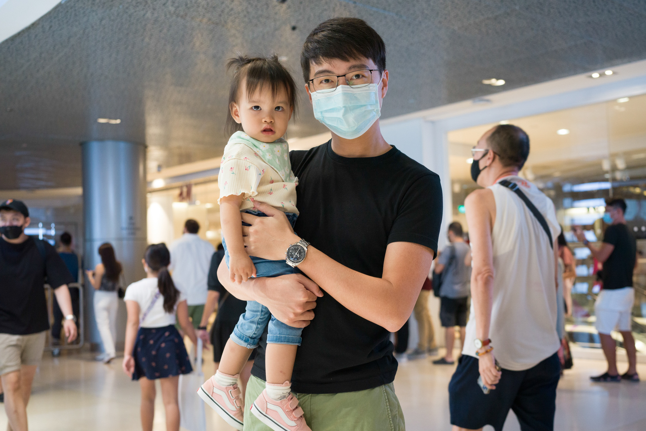 A man poses while wearing a watch and holding a child.