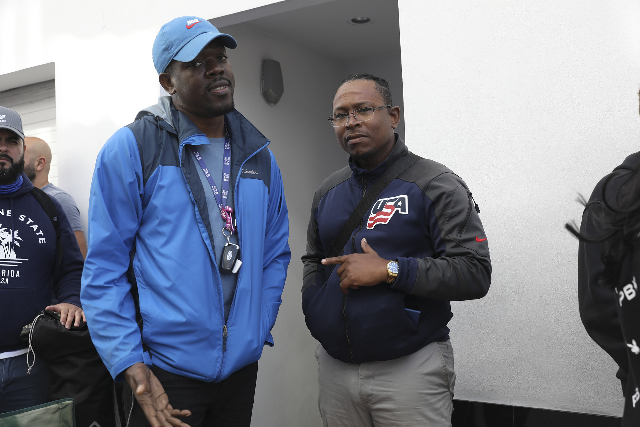 Two men pose while wearing watches.