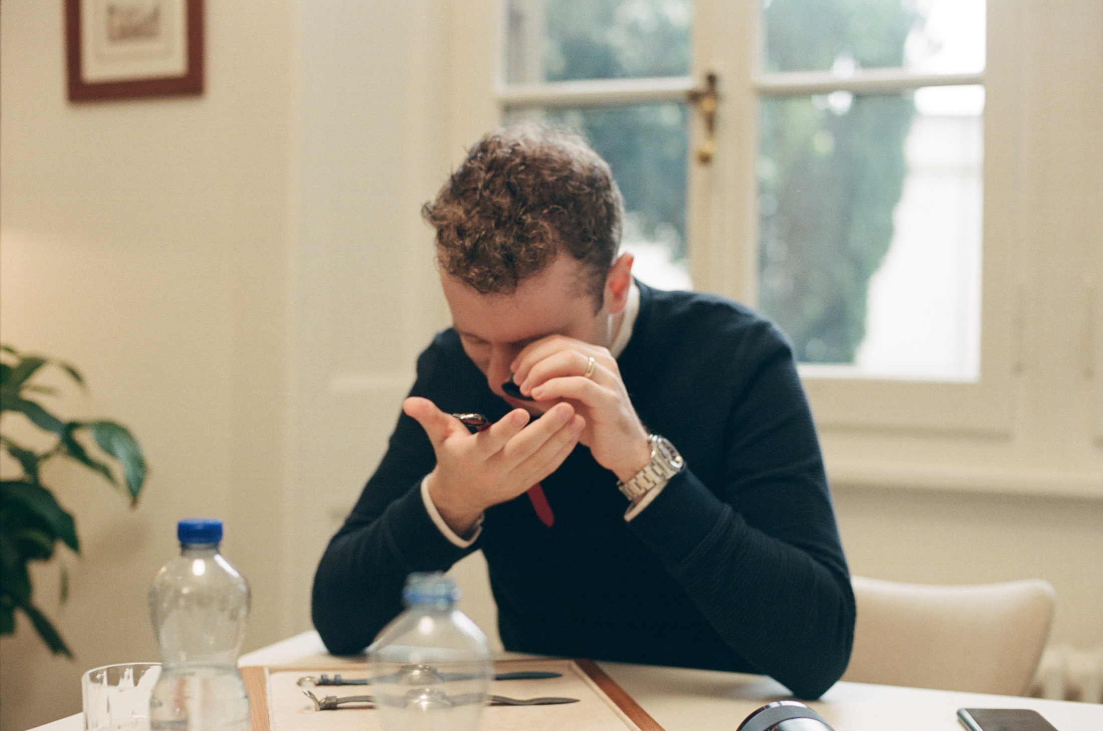 Danny looking at a watch with a loop. 