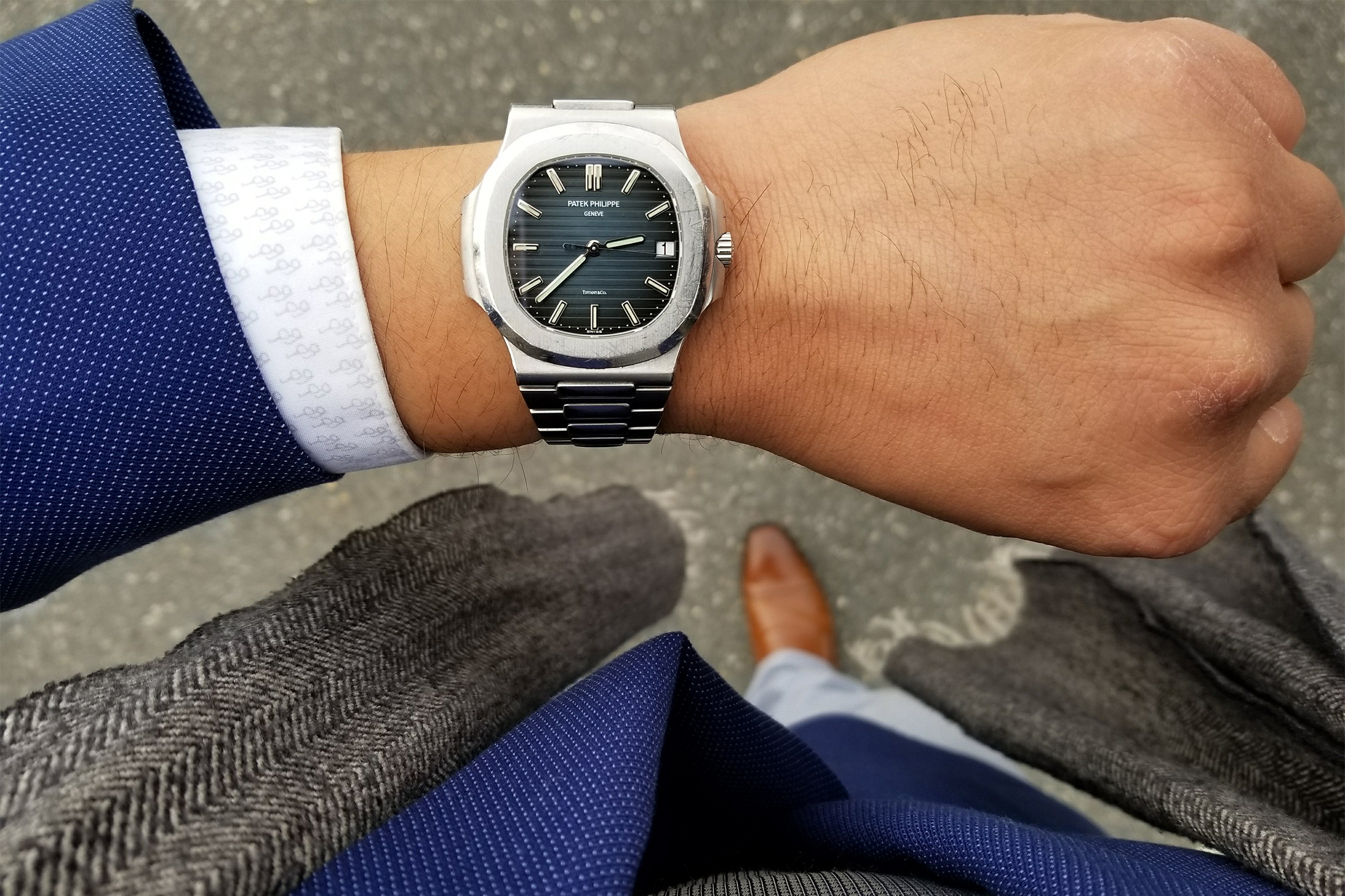 A man wears a Patek Philippe 5711 Nautilus with Tiffany stamp