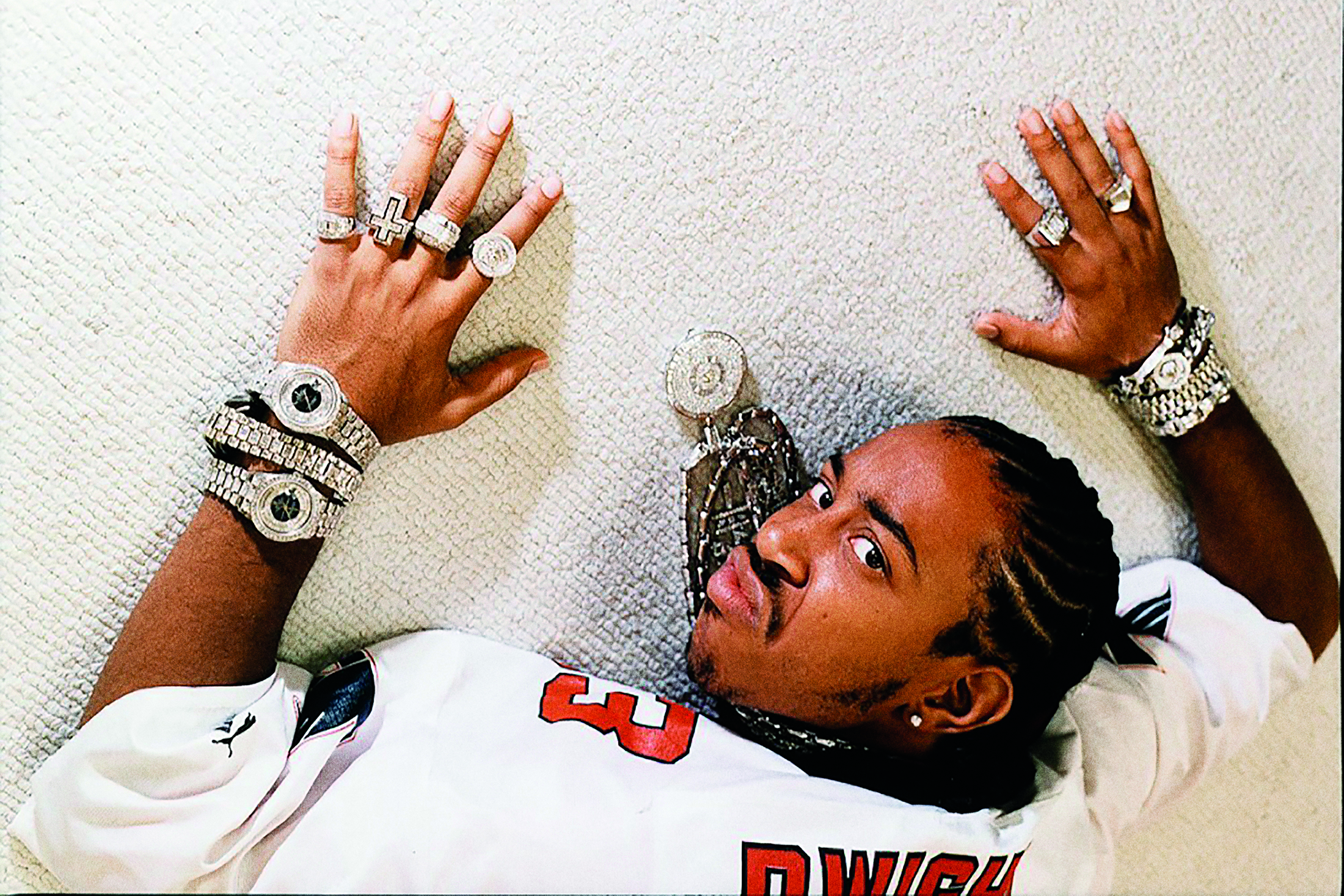 Rapper, Ludacris, laying on a white carpet wearing multiple watches.