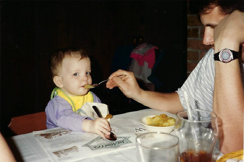 A man wearing a watch feeds a baby
