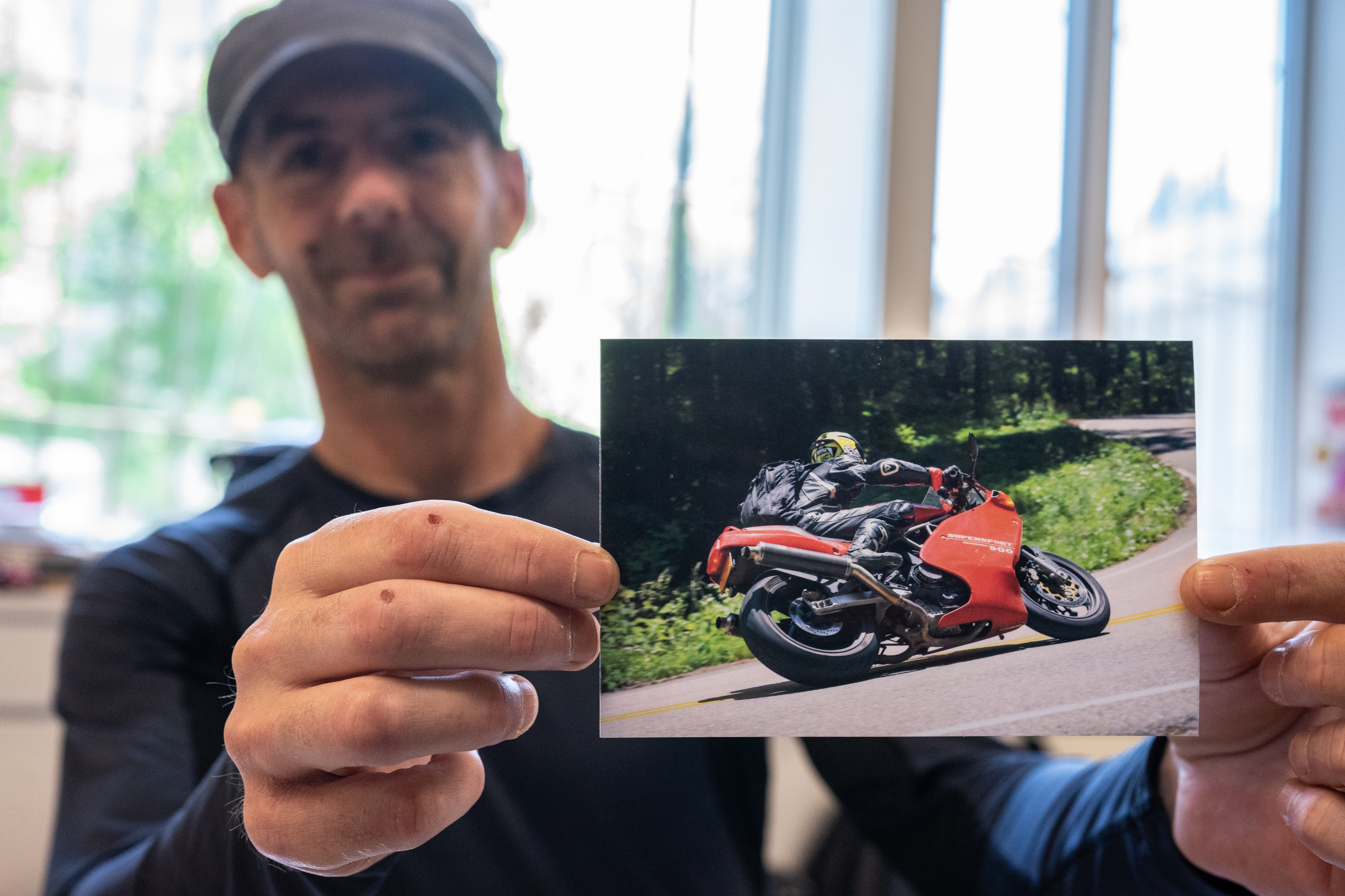A man holds a picture of a Ducati motorcycle.