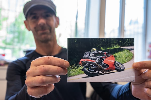 A man holds a picture of a Ducati motorcycle.