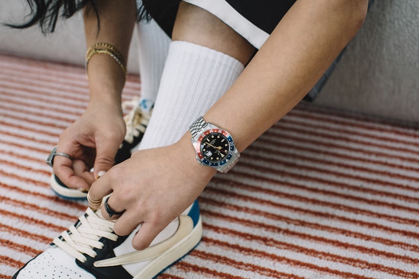 Someone tying sneakers while wearing a Rolex watch